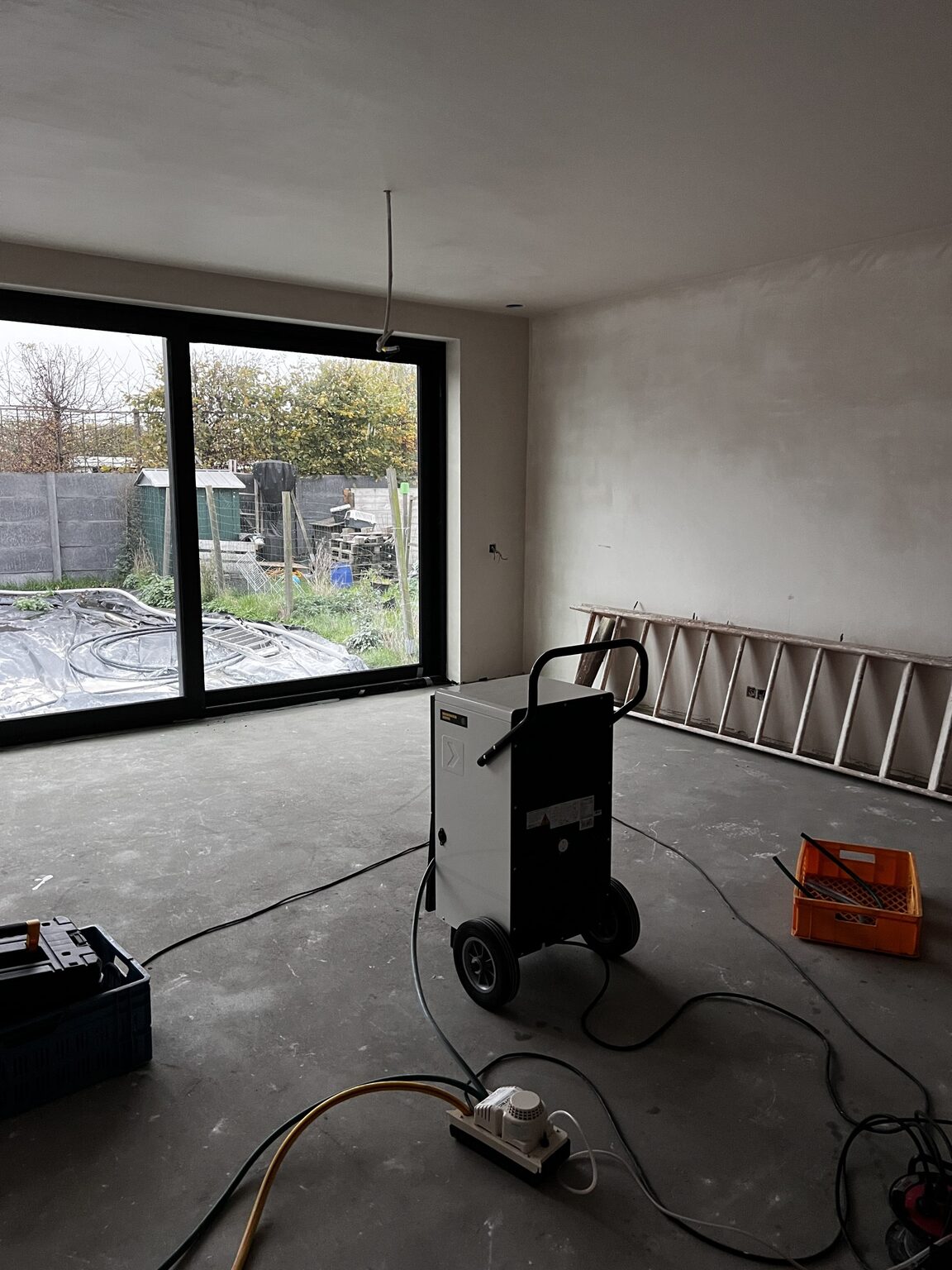 Droging van de woonkamer met bouwdroger en zicht op de tuin