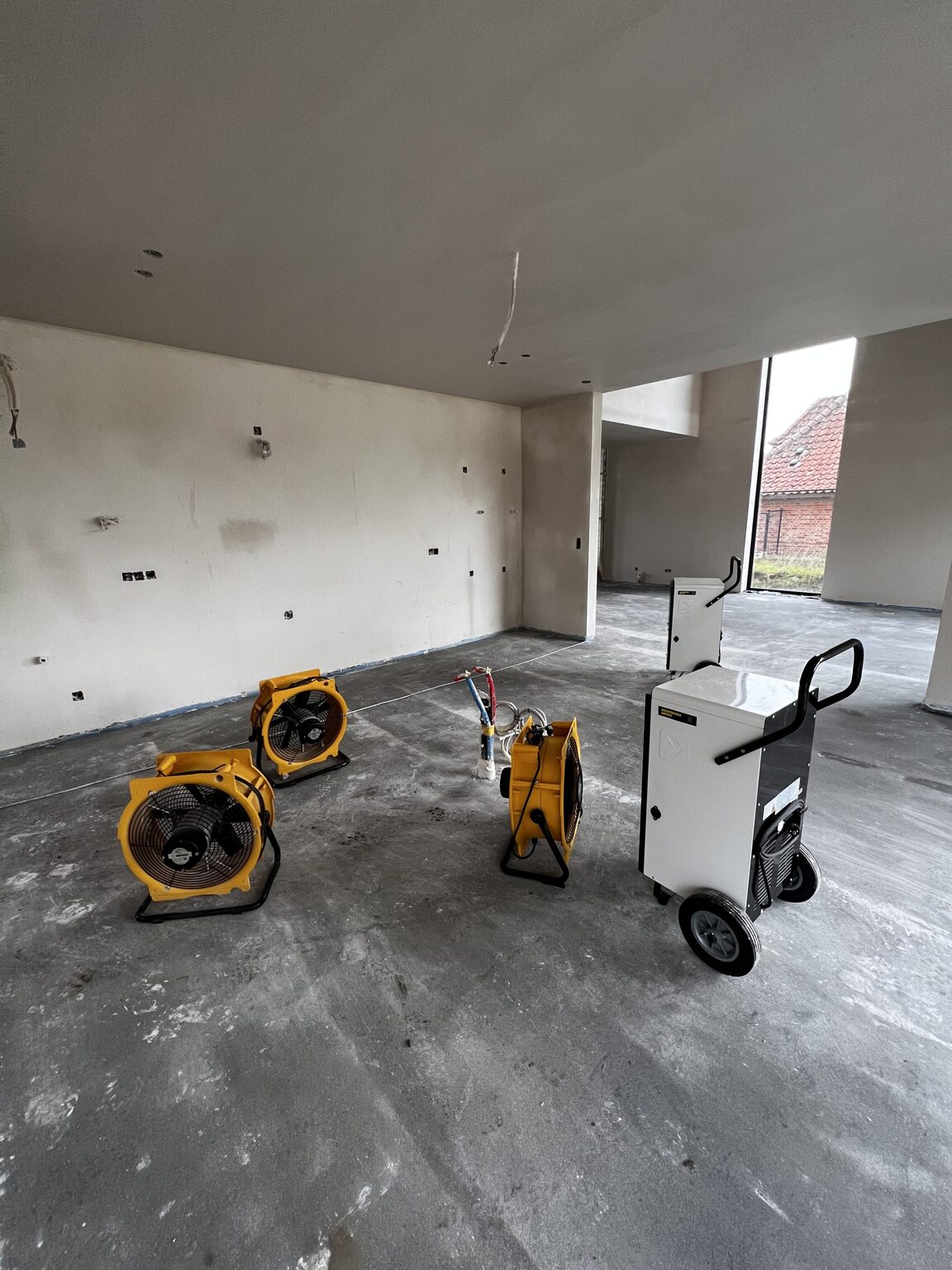 Bouwdrogers en ventilatoren opgesteld in de leegstaande leefruimte