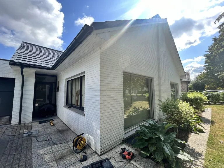 De behandelde witte woning in Aartselaar met droogapparatuur op het terras